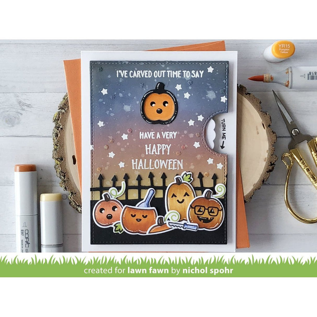 Halloween-themed card with pumpkins and text on a wooden surface with craft supplies.