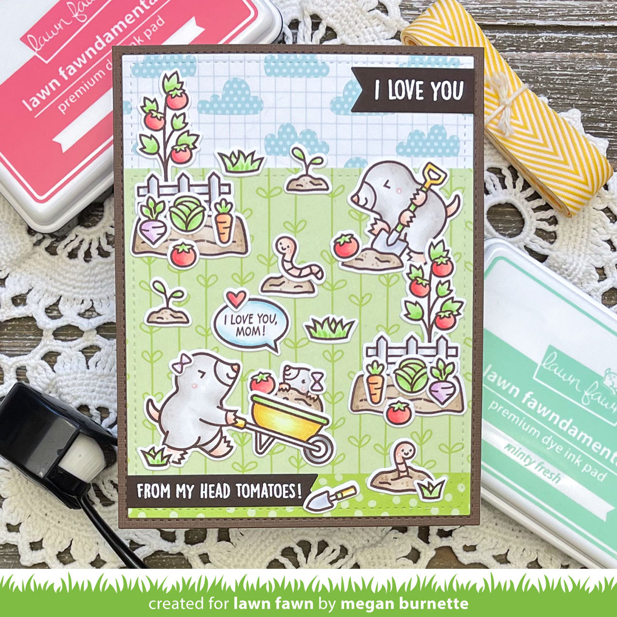 Card with moles and tomato plants, surrounded by stamping supplies on a wooden surface.