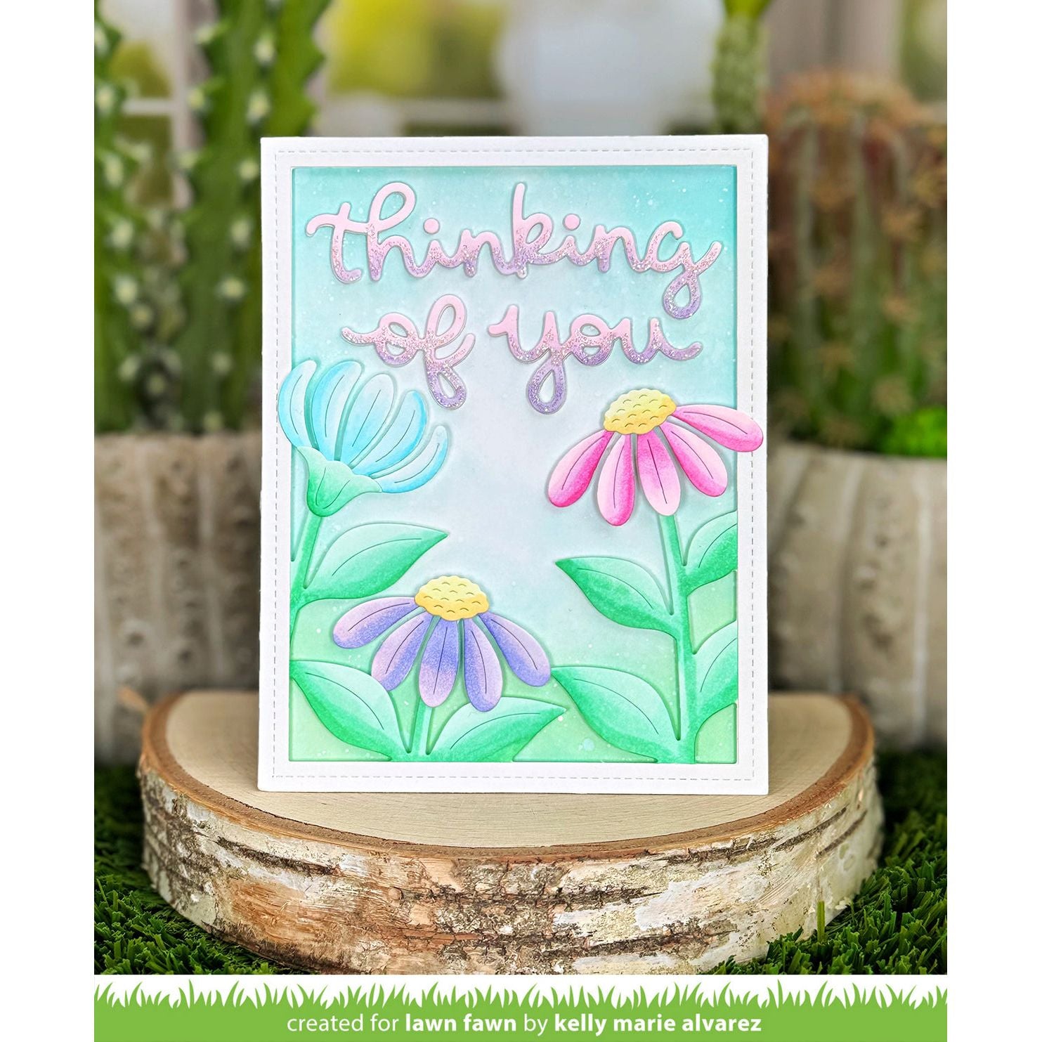 Card with flowers and 'thinking of you' text on a wooden stand with plants in the background