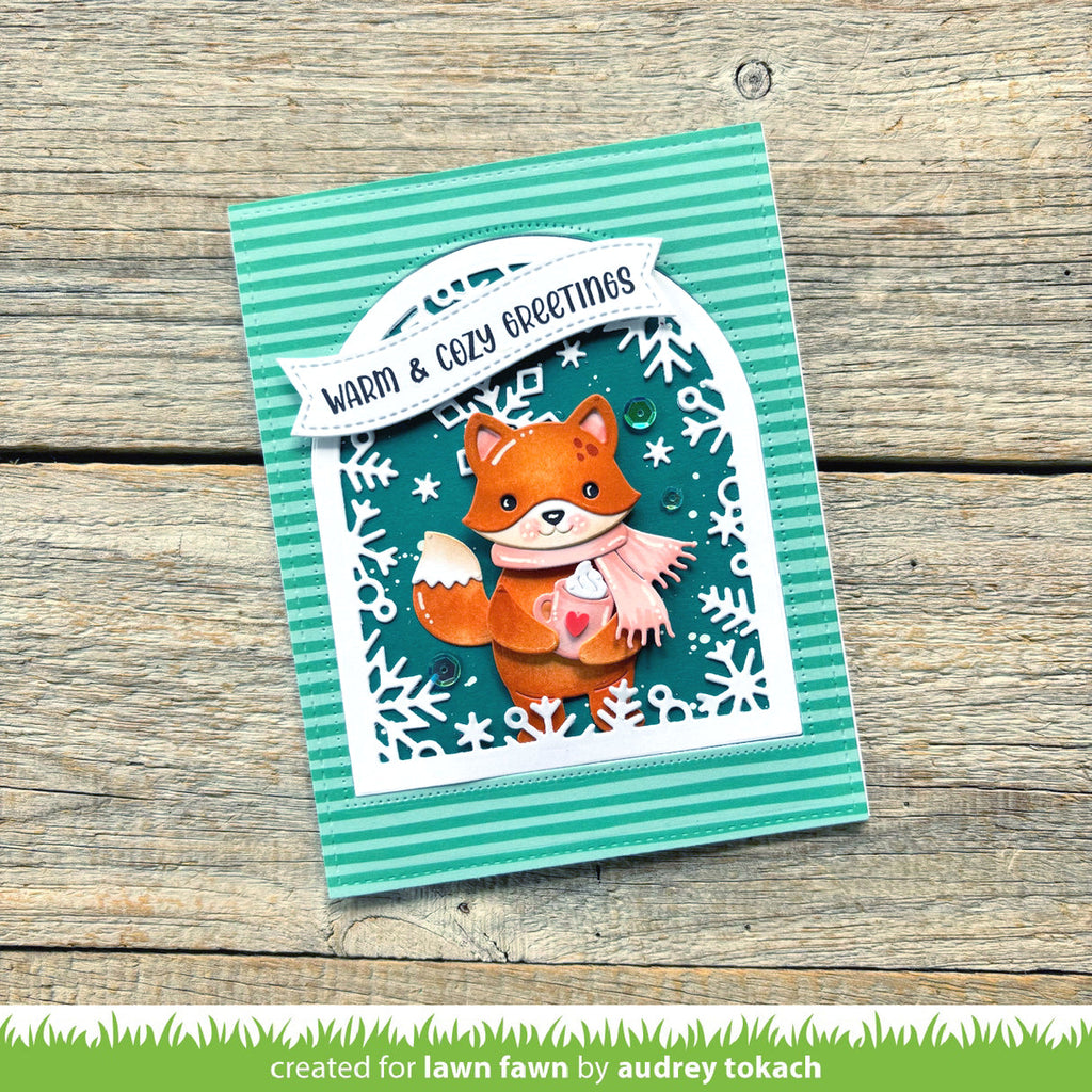 Card with a fox illustration and 'Warm & Cozy Greetings' text on a wooden surface