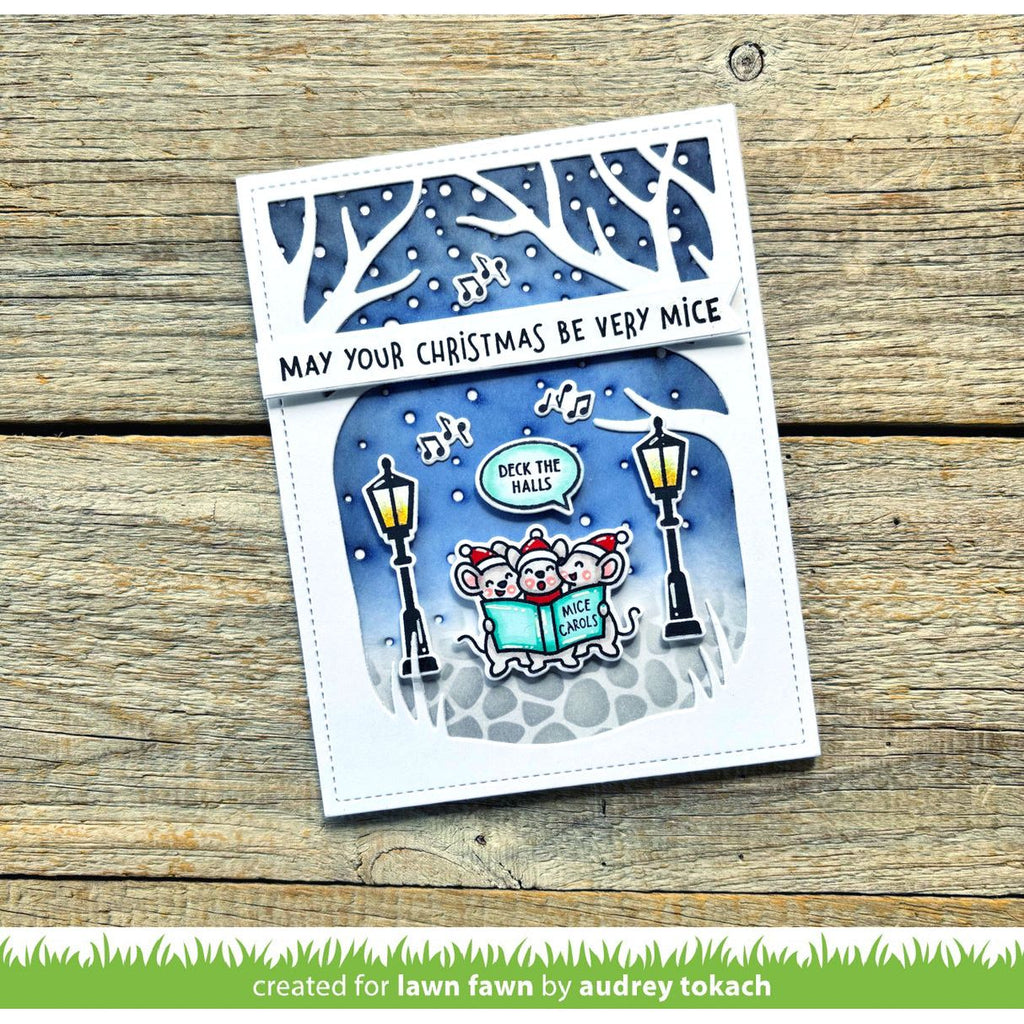 Christmas-themed card with cartoon mice and festive text on a wooden surface