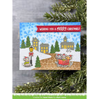 Christmas card with snowy village scene and festive text, surrounded by greenery.