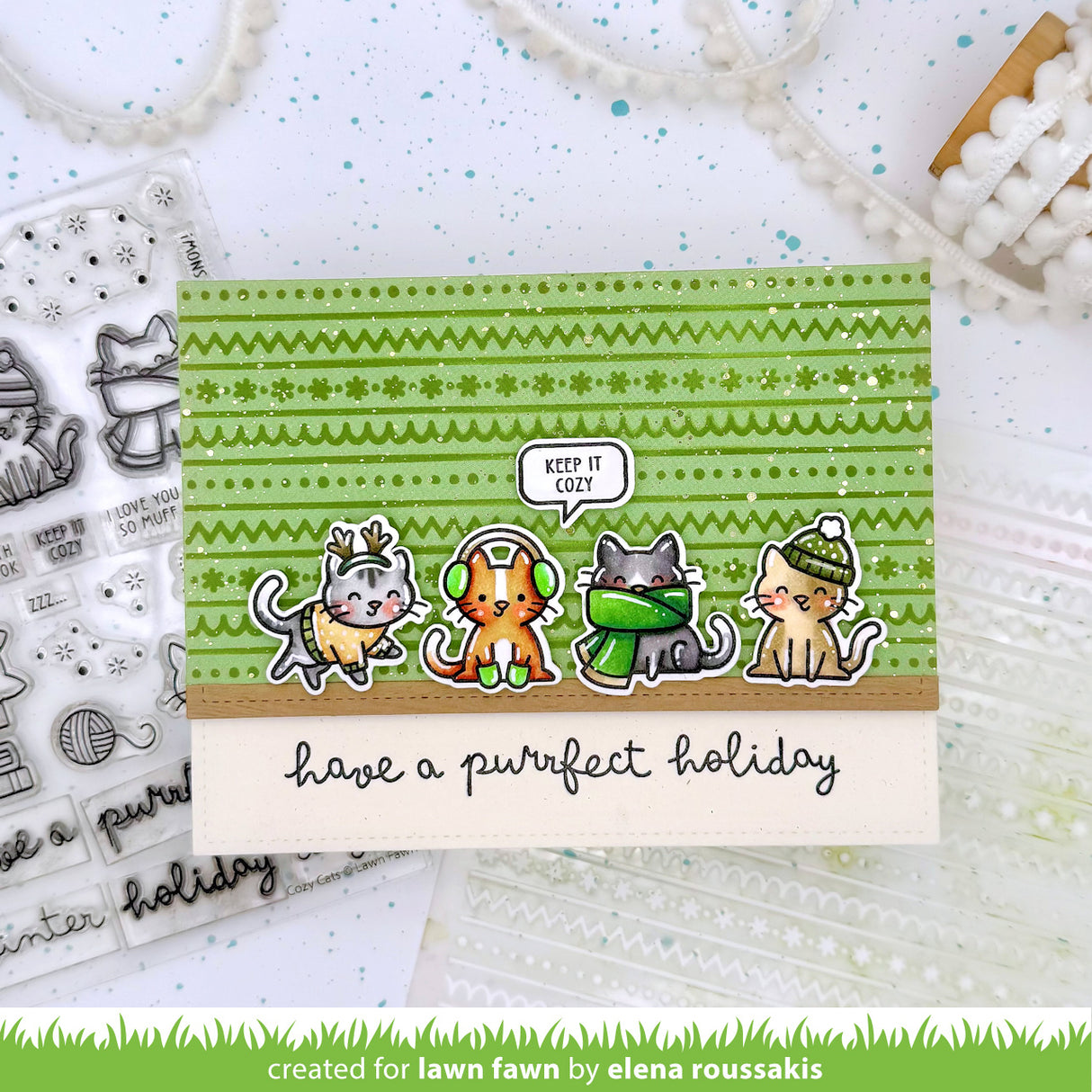 Card with four cats wearing winter accessories and text 'have a purrfect holiday' on a green patterned background.
