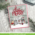 Christmas card with 'Be Merry' text and cartoon animals on a wooden surface with holiday decorations.