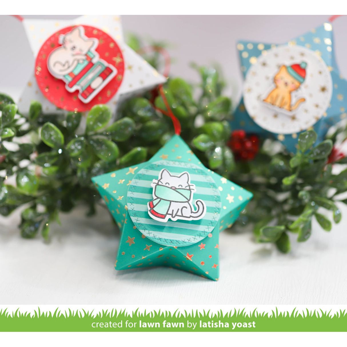 Star-shaped Christmas ornaments with cat designs on a green leafy background