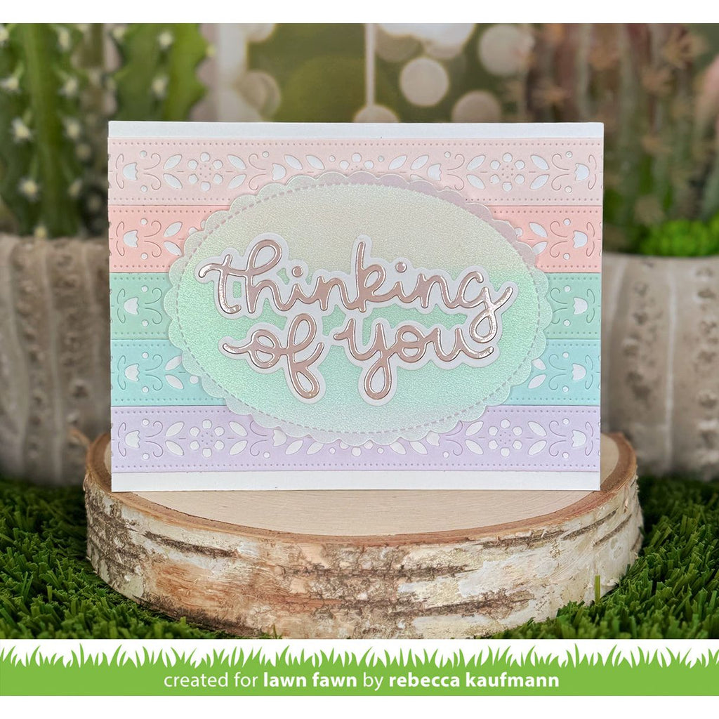Greeting card with 'thinking of you' text on a decorative stand with plants in the background