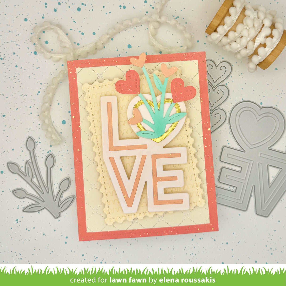 Card with 'LOVE' cutout and decorative elements on a textured surface with crafting tools.