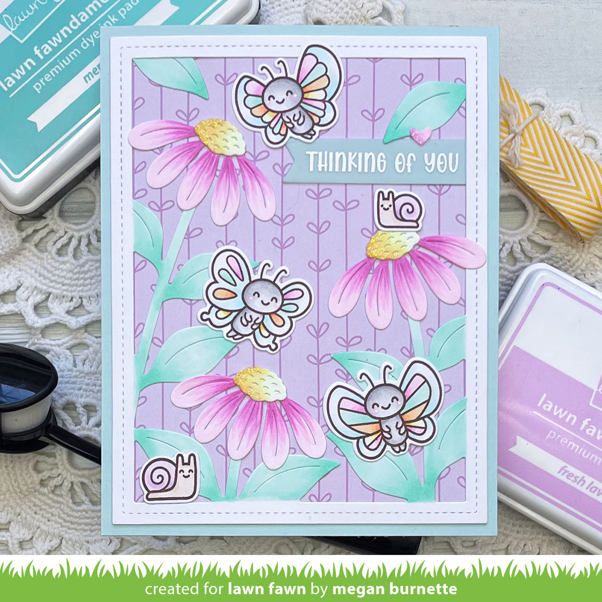 Card with butterflies and flowers on a purple background, surrounded by crafting supplies.