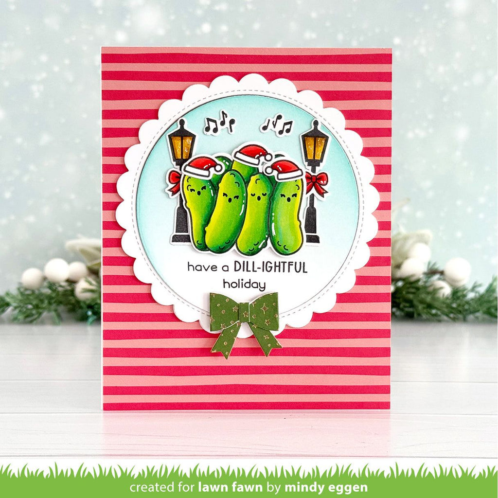 Holiday card with pickles wearing Santa hats on a red and white striped background.