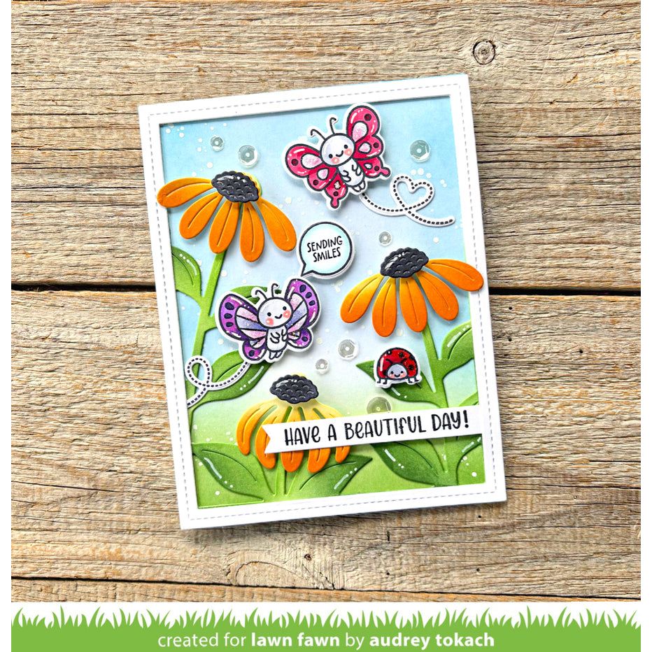 Colorful card with butterflies and flowers on a wooden surface, created by Audrey Tokach for Lawn Fawn.