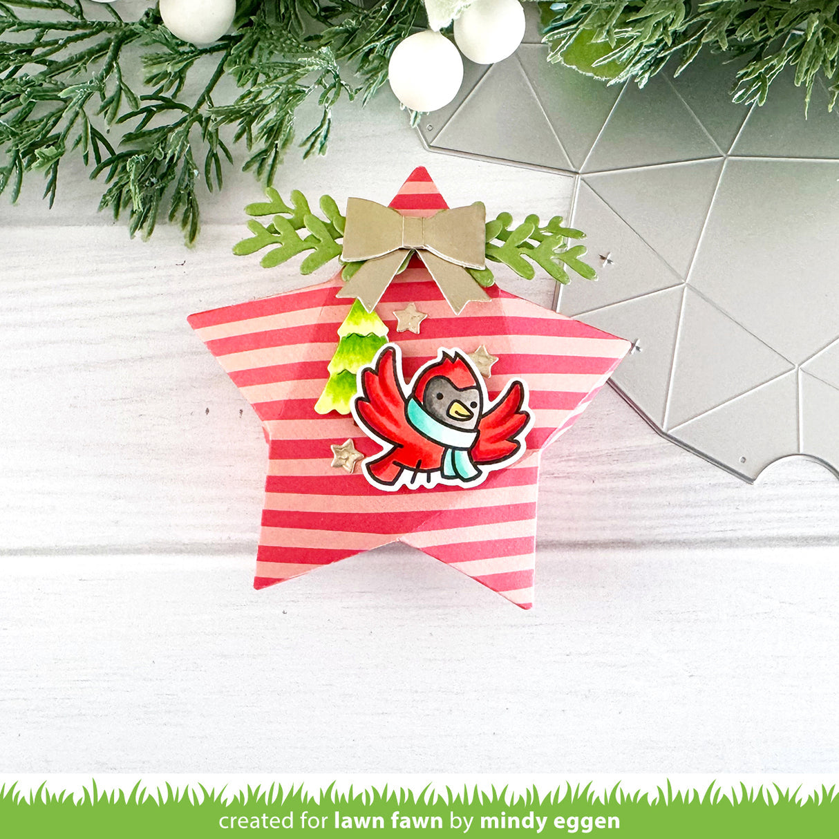 Star-shaped ornament with a cardinal design and red and white striped pattern, surrounded by greenery and lights.