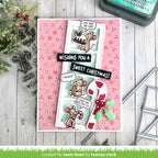 Christmas-themed card with teddy bear illustrations and candy cane on a pink background, surrounded by stamping tools.