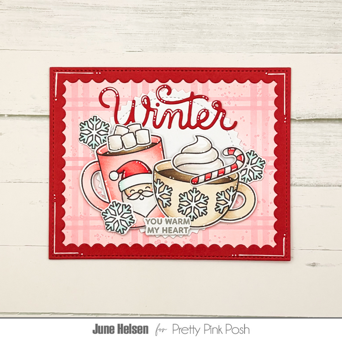 Pretty Pink Posh Warm Heart STAMPtember Exclusive red christmas card from June Helson containing the word winter in the background and the sentiment you warm my heart in the foreground. two cups of cocoa are in the center.