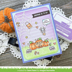 Halloween-themed card with pumpkins and spider on a wooden surface with a pumpkin and doily.