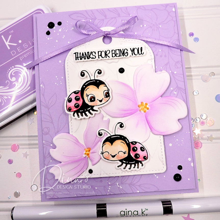 Purple Greeting card with ladybug design and 'Thanks for being you' text, featuring Gina K. Design Studio branding.