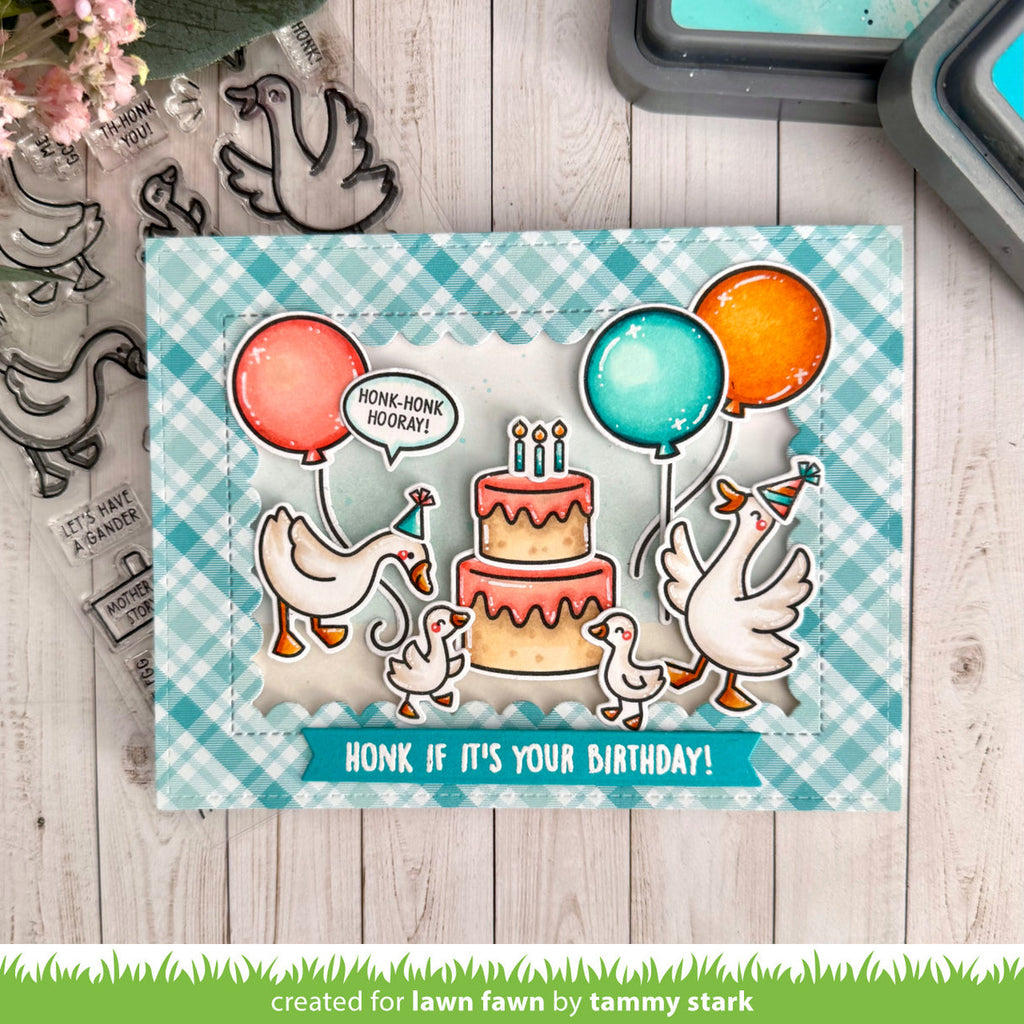 Card with ducks and birthday cake design on a checkered background, surrounded by stamping tools.