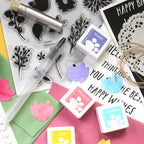 Stamping tools and ink pads on a colorful background with text and decorative elements.