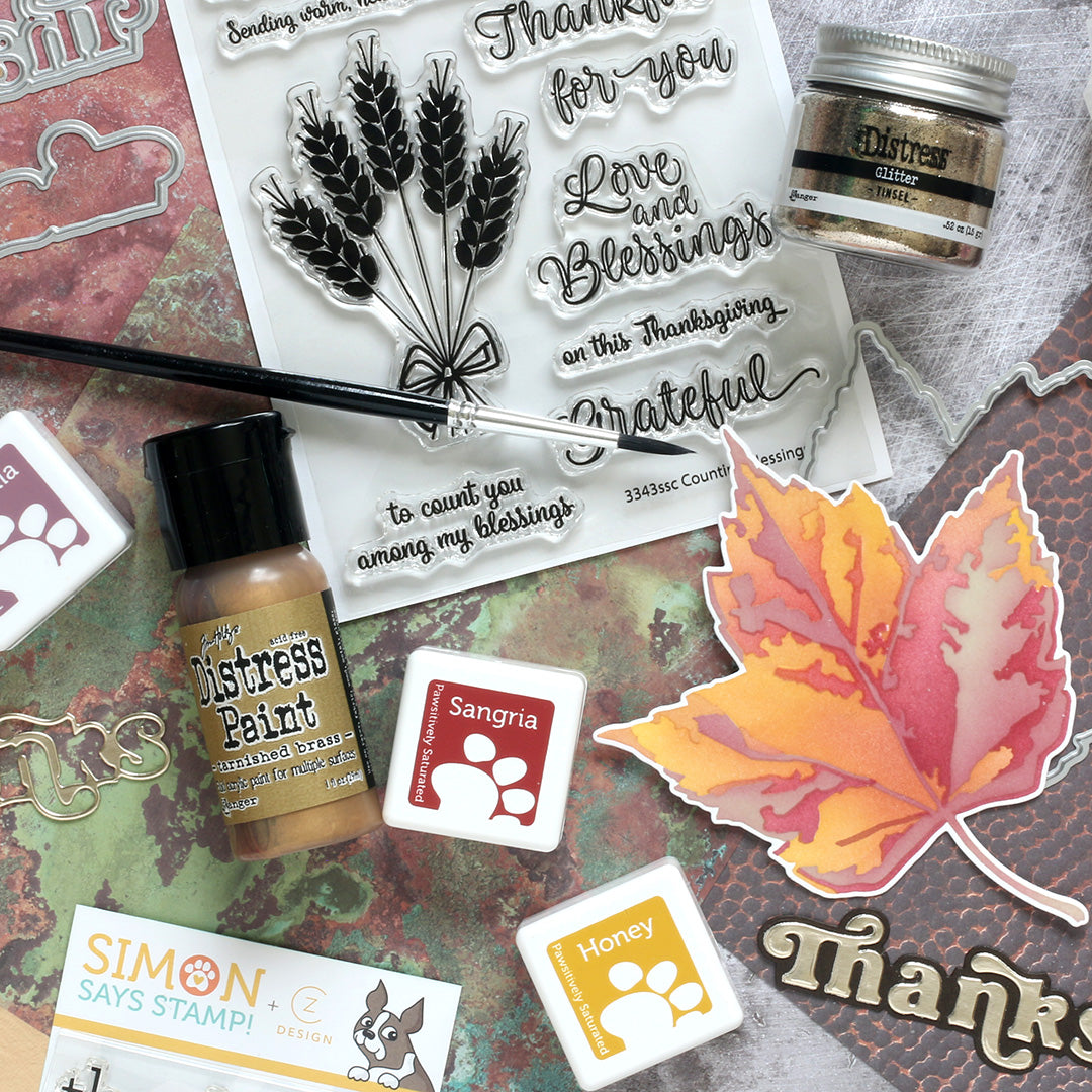 Stamp set with leaves, text, and distress ink on a textured surface