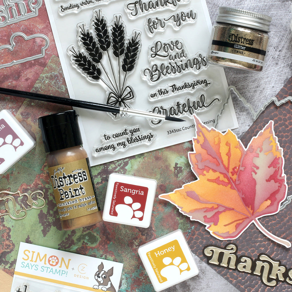 Stamp set with leaves, text, and distress ink on a textured surface
