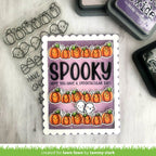 Halloween-themed stamp with pumpkins and text on a wooden surface with stamping supplies.