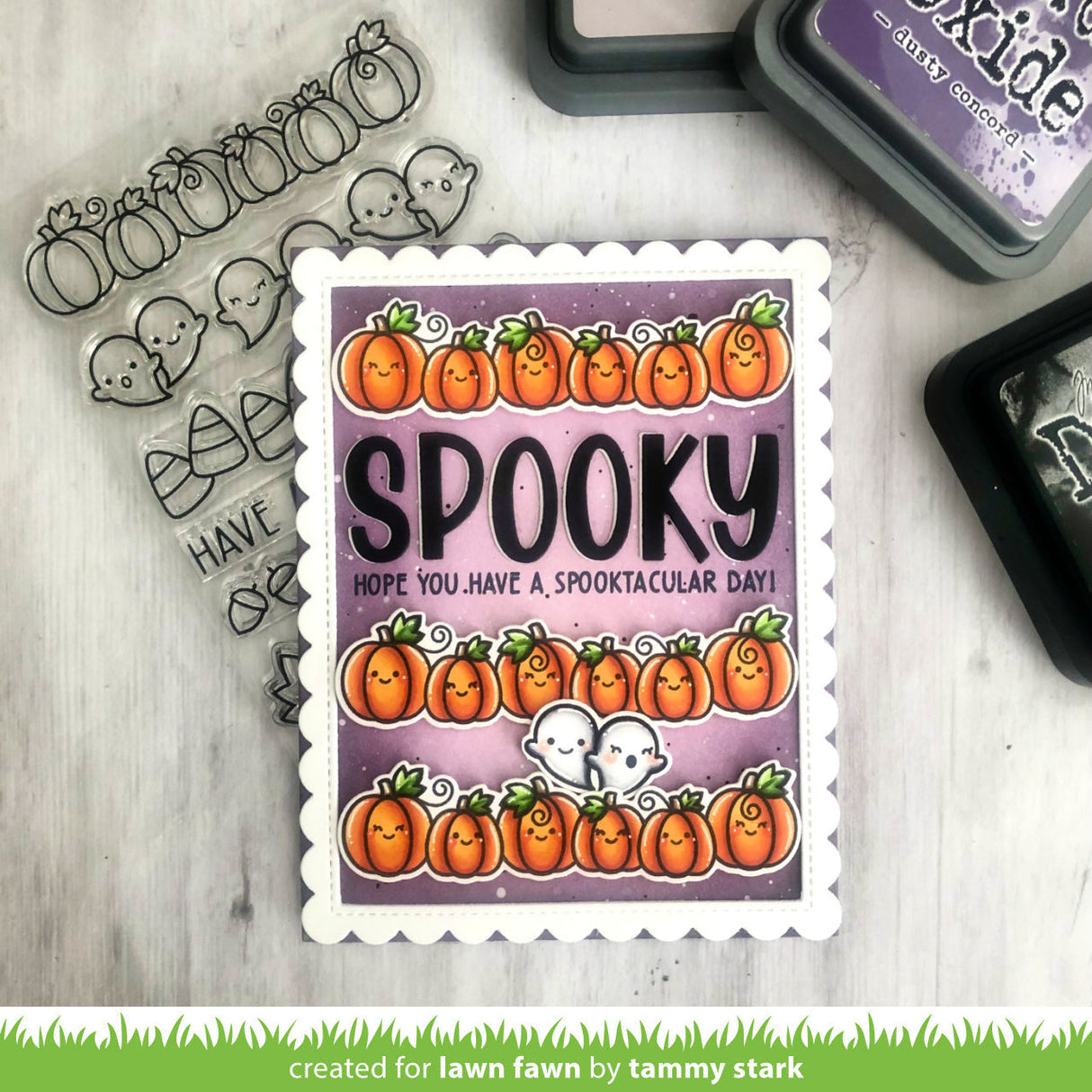 Halloween-themed stamp with pumpkins and text on a wooden surface with stamping supplies.