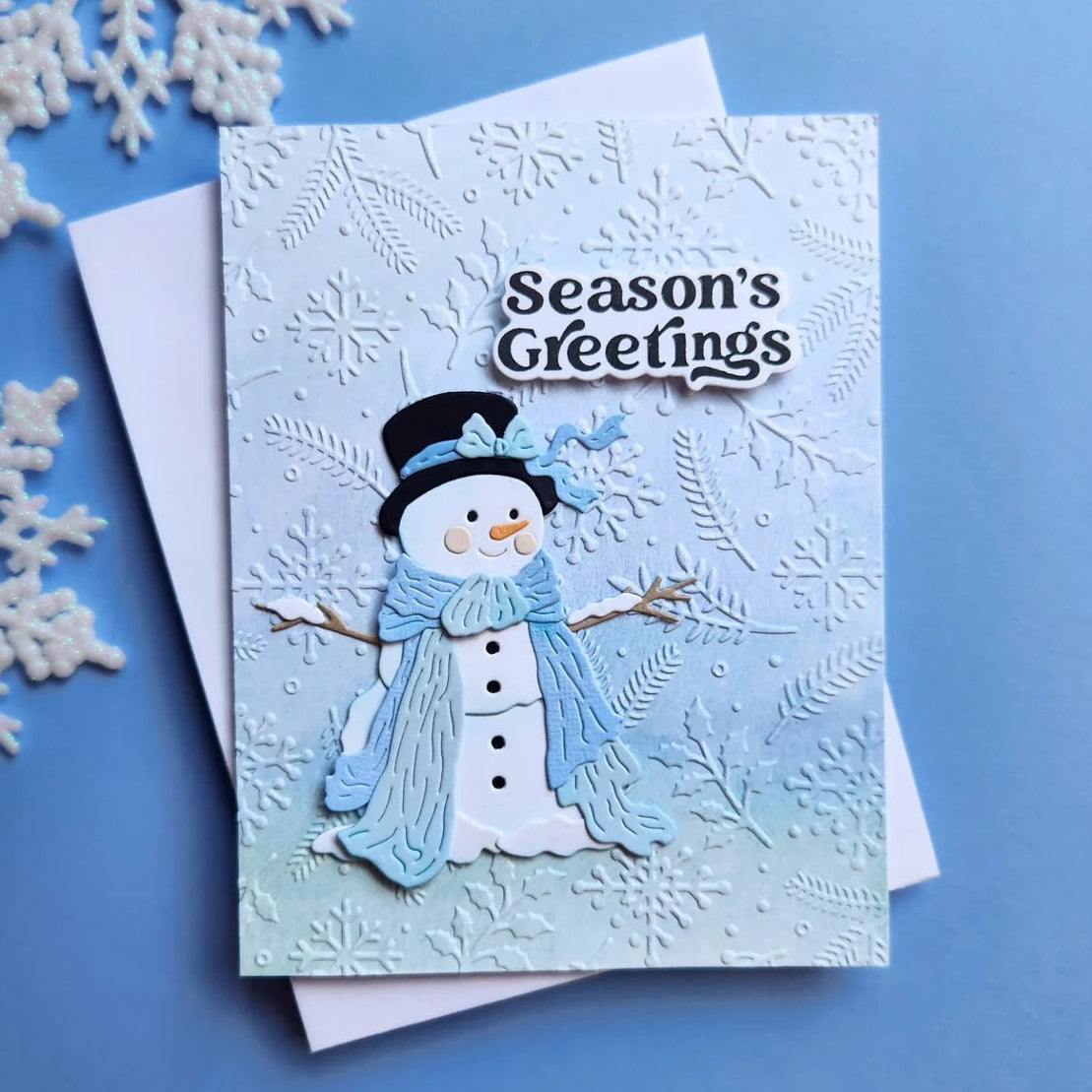 Spellbinders Sweet Snowman Etched Dies s4-1563 hat with blue bow blue scard snowflake and leaves background seasons greetings card deborah hellman