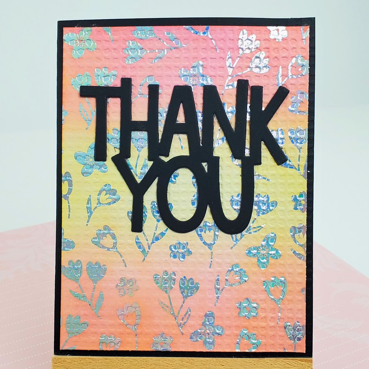 Card with 'THANK YOU' text on a floral patterned background